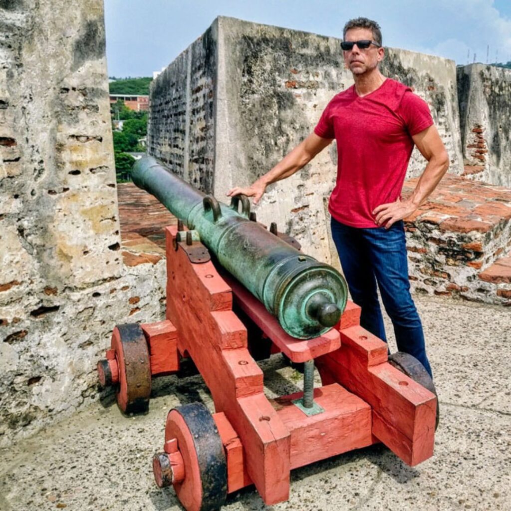 Eric at Castillo San Felipe de Barajas next to cannon in Cartagena, Colombia.