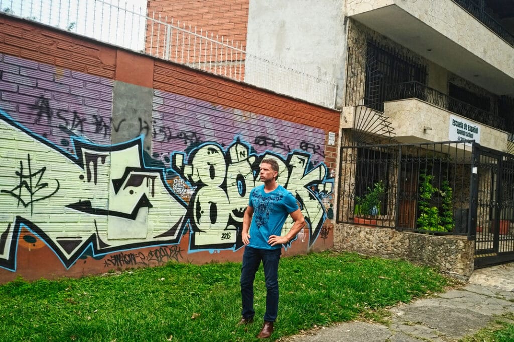Eric is standing next to the Spanish School that is on one side of the building where Pablo Escobar was killed on December 2, 1993, on the barrel tiled roof in Medellín, Antioquia Colombia.