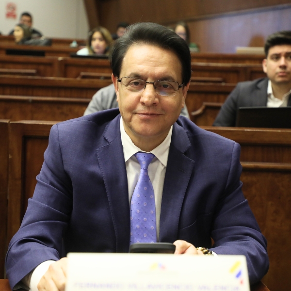 The late presidential candidate, Fernando Villavicencio is in a court room, facing the camera wearing glasses, a blue suit and light purple tie.