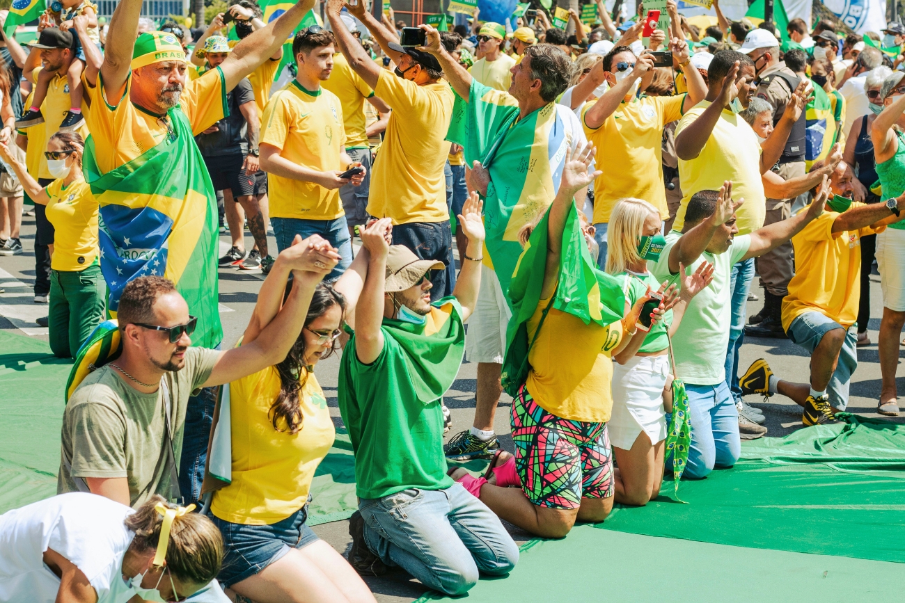 Soccer or futebol fans in Brazil, all dressed in yellow and green, some kneeling, praying for something good to happen.