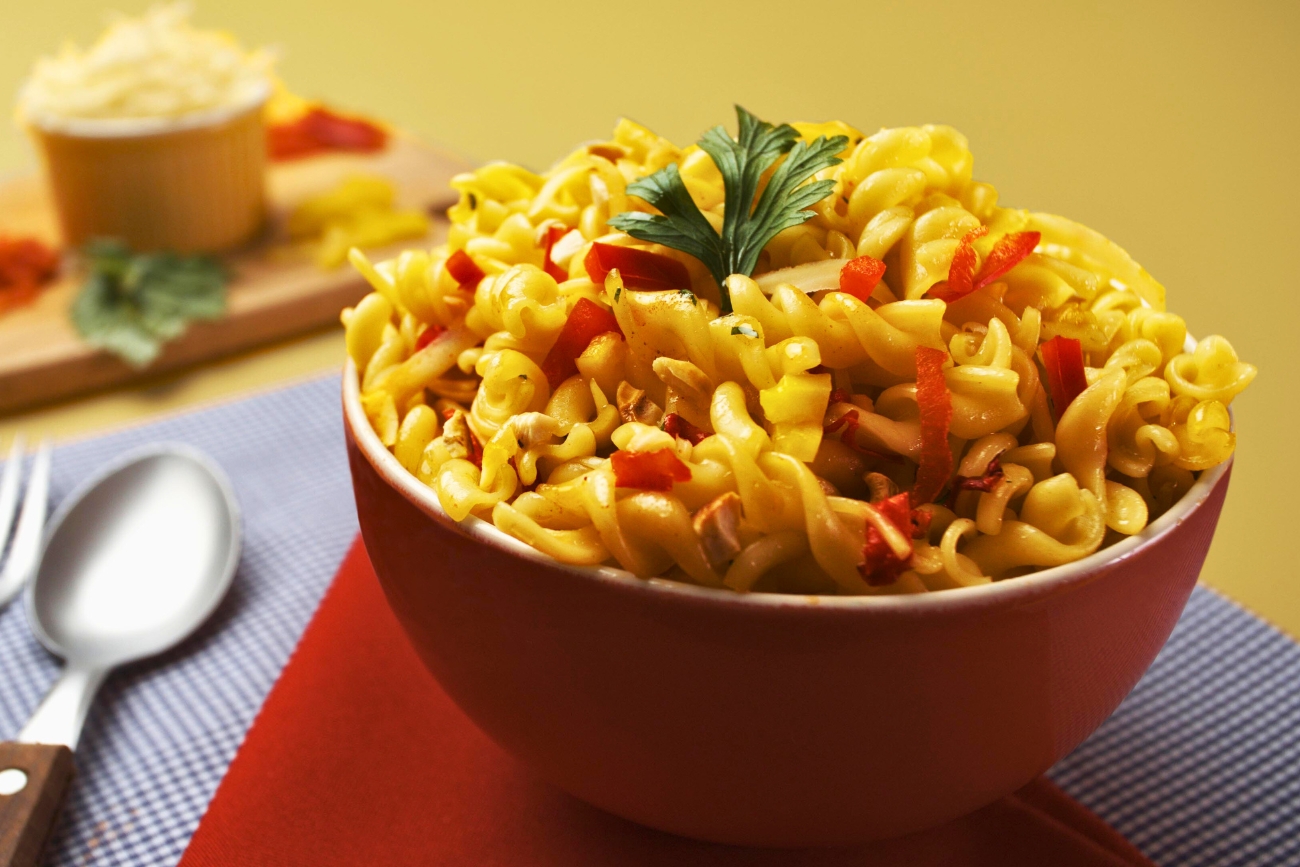 Ensalada de Macarrão in a bowl with silverware to the left.