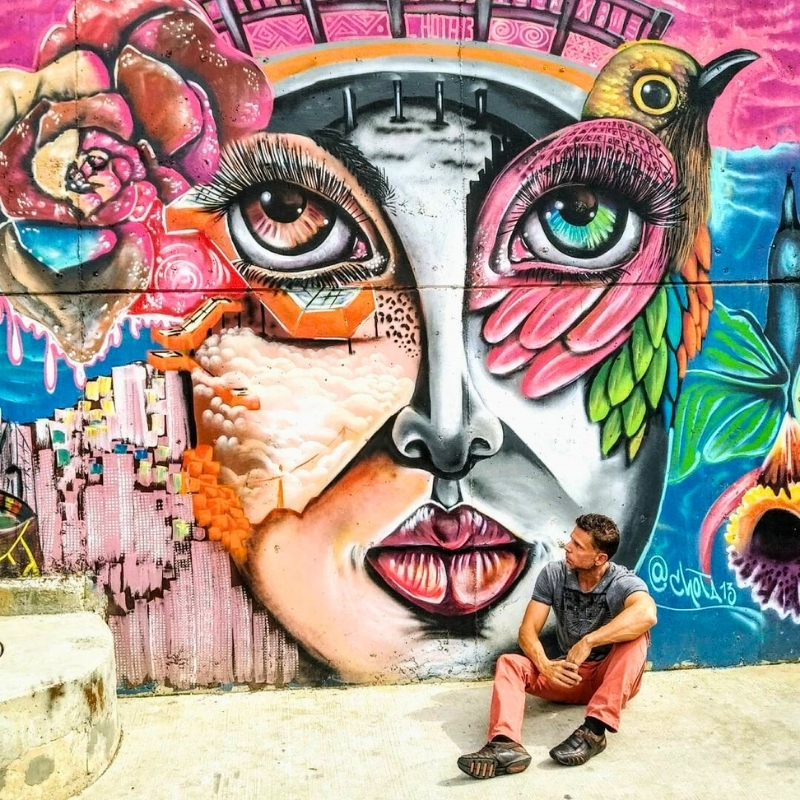 Eric sitting and admiring the colorful wall art in San Javier, Comuna 13 in Medellín, Antioquia, Colombia.
