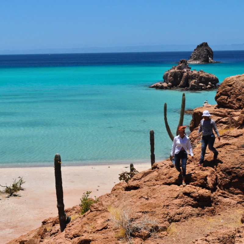 Two women walking with sea in the background of Isla Espíritu Santo in La Paz, Baja California Sur, Mexico.