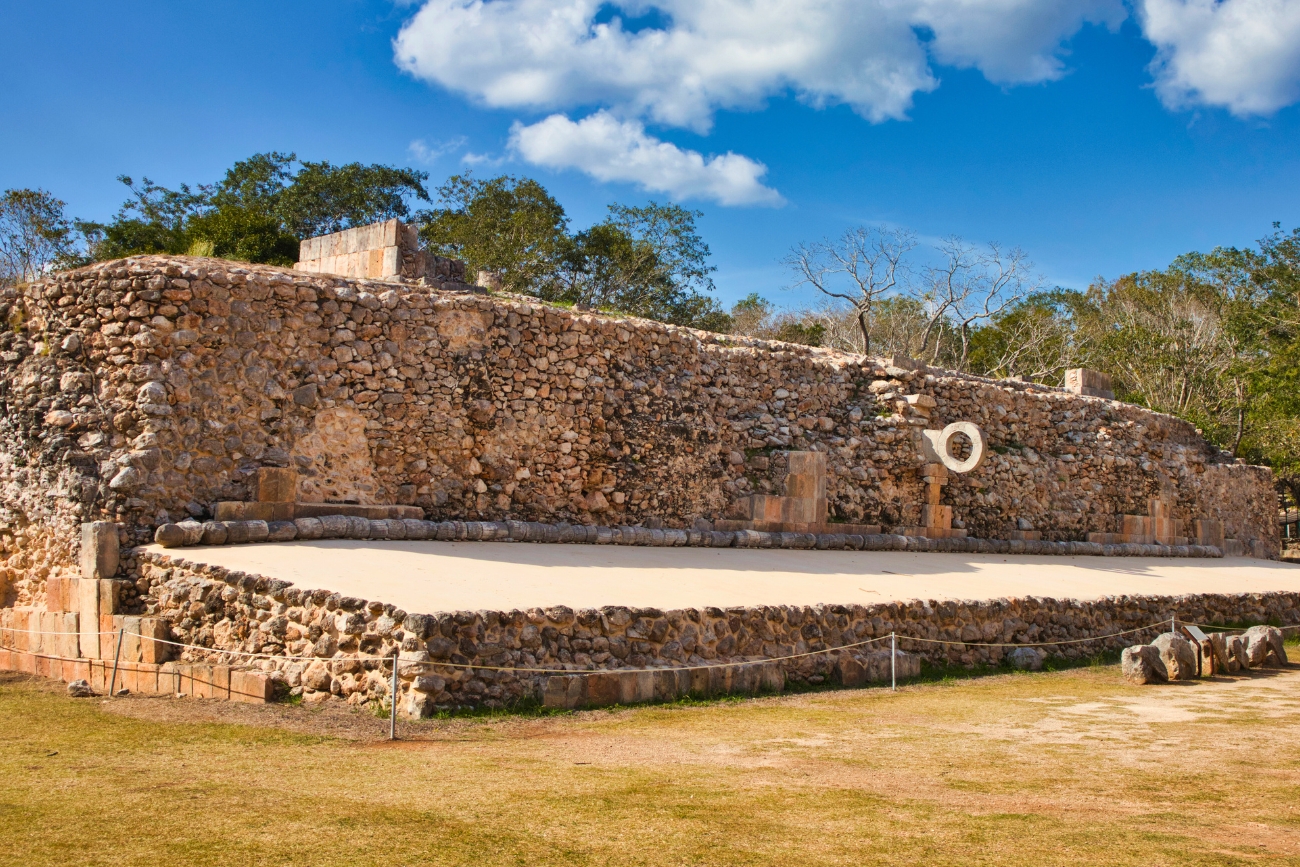 Pok-ta-pok Maya Ball Court with hoops visible on a sunny day with verdant landscape in Uxmal, Yucatán, Mexico.