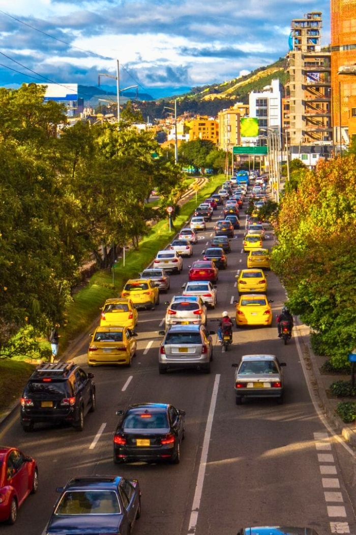 Traffic jam with cars, taxis and a couple motorcycles on a partly cloudy day in Bogotá, one of the best cities to live in Colombia for expats.