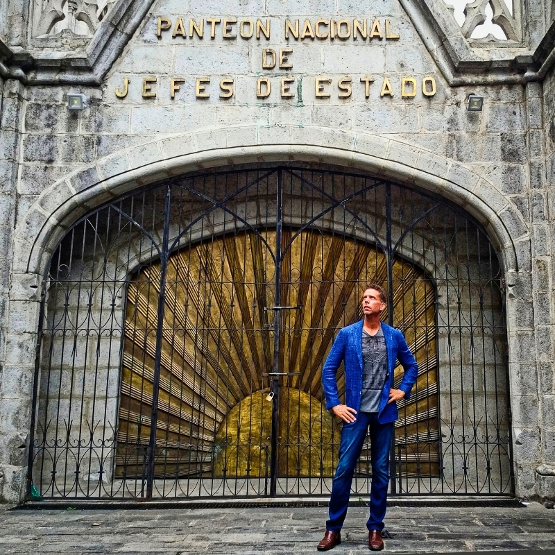 Eric, wearing blue blazer and jeans, standing in front of the Panteón Nacional de Jefes de Estado at the Basílica del Voto Nacional in Quito, Pichincha, one of the best cities to live in Ecuador.