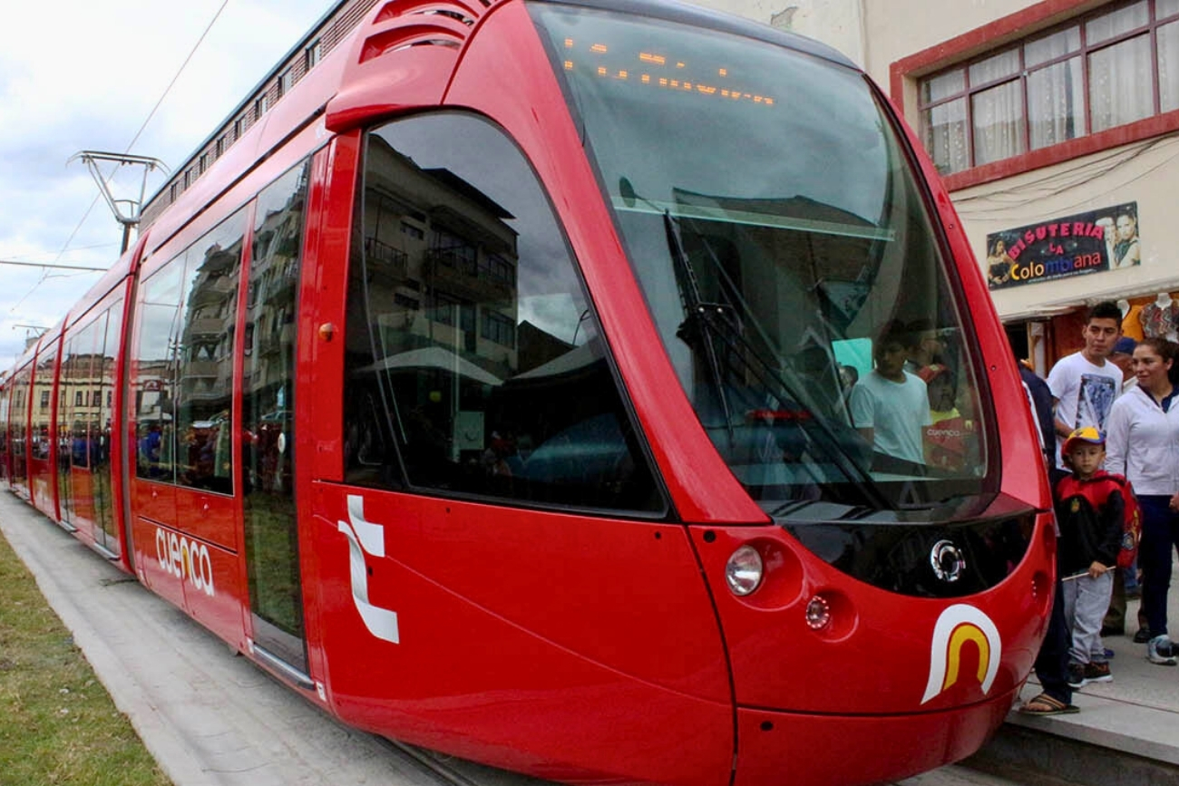 People to the right of the red tram called tranvía in Cuenca, Azuay, Ecuador, one of the best cities in Ecuador for expats to live.