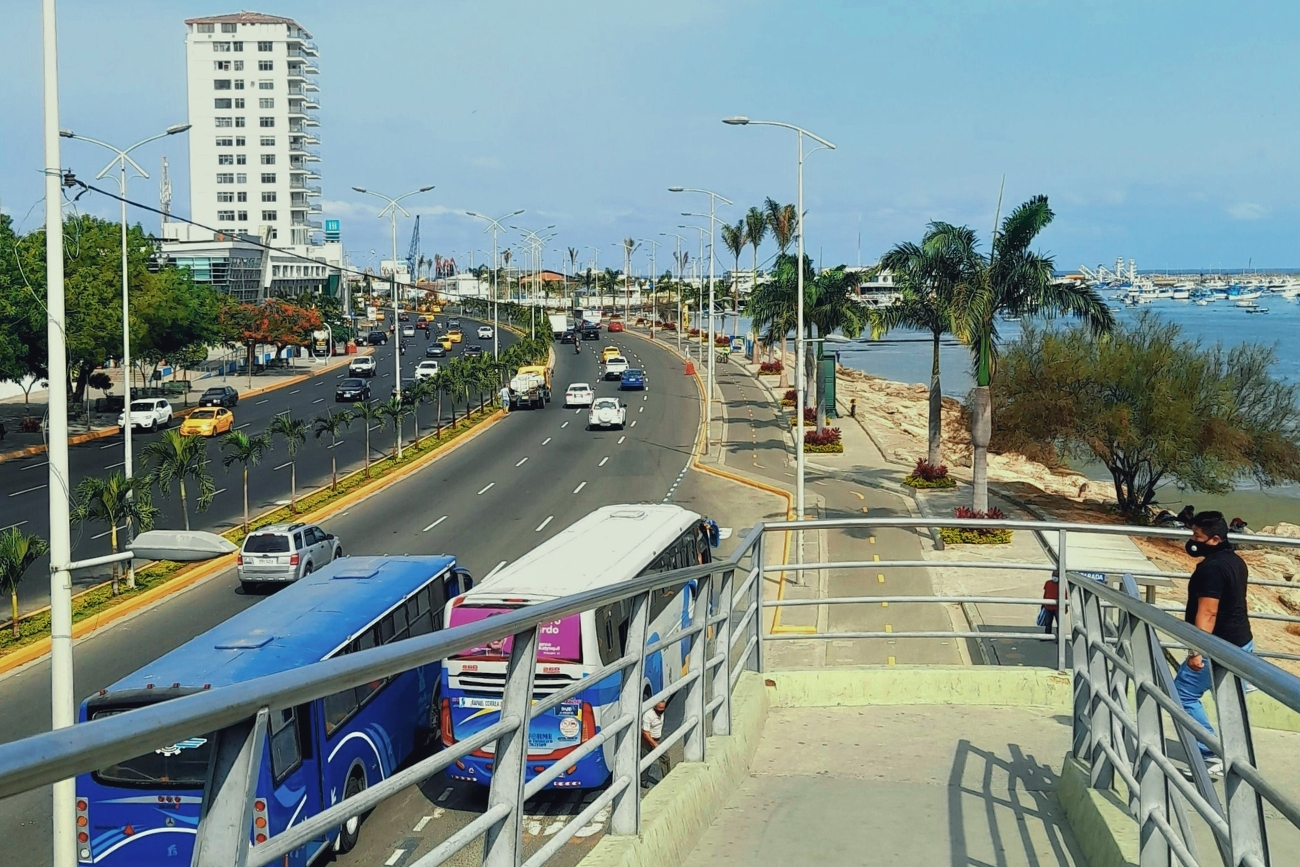 A highway with a pedestrian bridge, buses and cars along th coast in Manta, Ecuador.